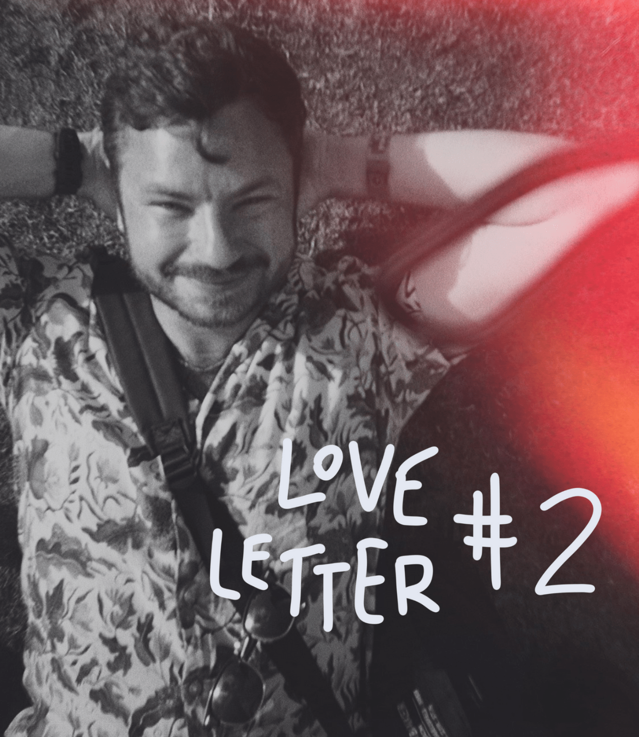 Man laid on his back on the ground with his arms folded behind his head smiling into the camera